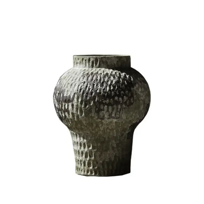 A dark gray coarse pottery vase with hammered texture and narrow neck for rustic home decor by decorbites