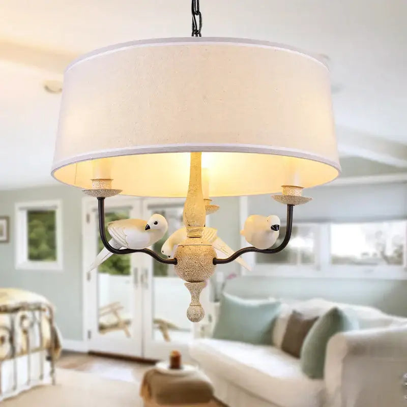 A rustic wood and iron decorbites bird lamp chandelier with cream fabric shade and sculpted white birds in aged brass finish