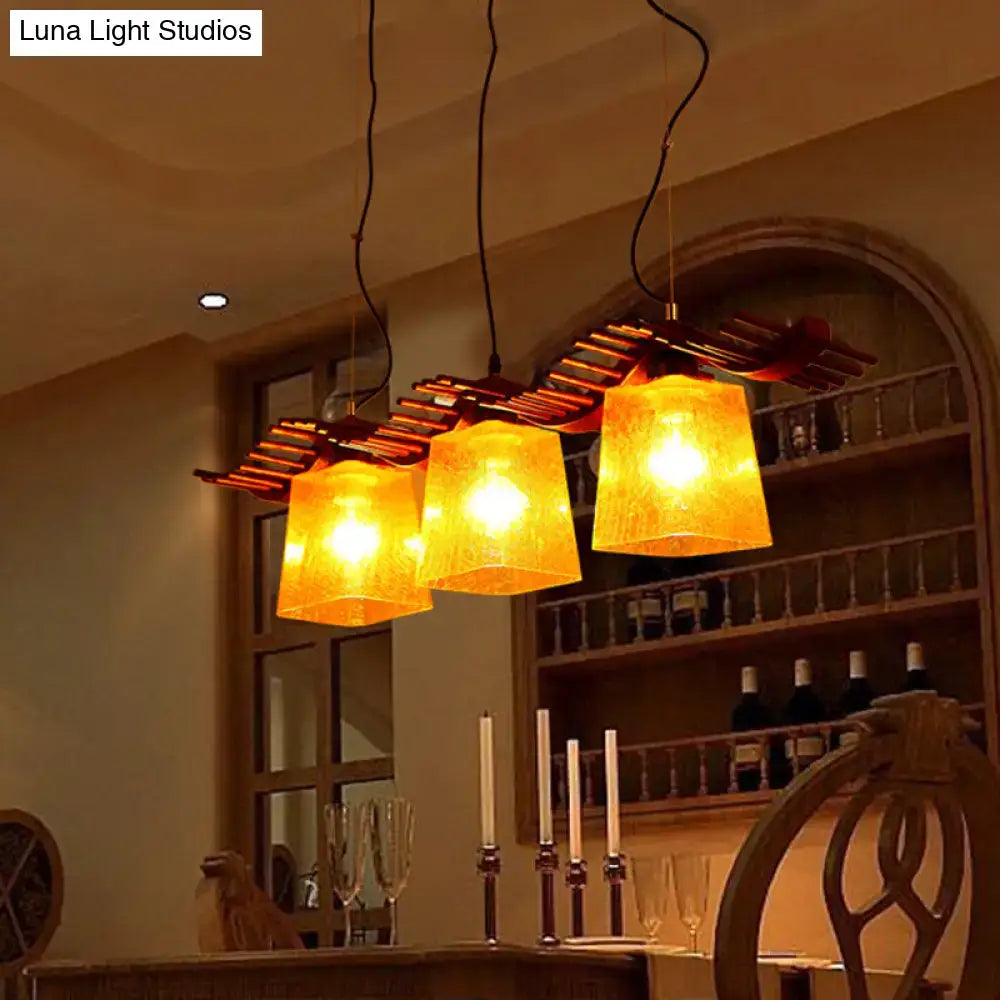 DecorBites rustic wood island lamp with warm yellow crackle glass shades hanging over a dining room island