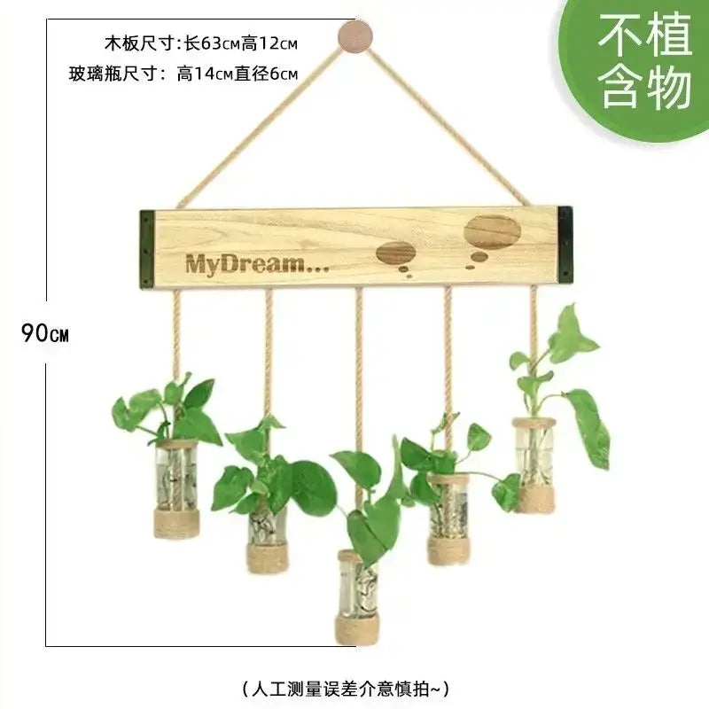 Light-colored wooden stand with five glass planter vases hanging by ropes containing small green plants for wall decor