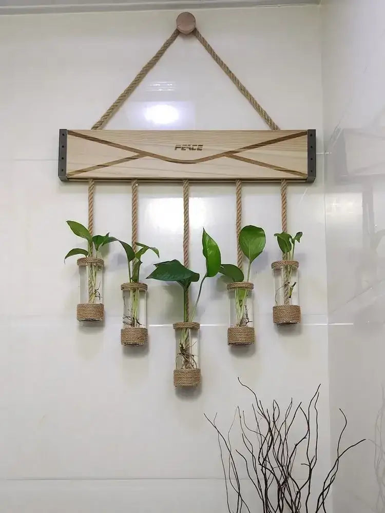 Light wood wall-mounted wooden stand with rope suspension and five glass planter vase vials holding green plants