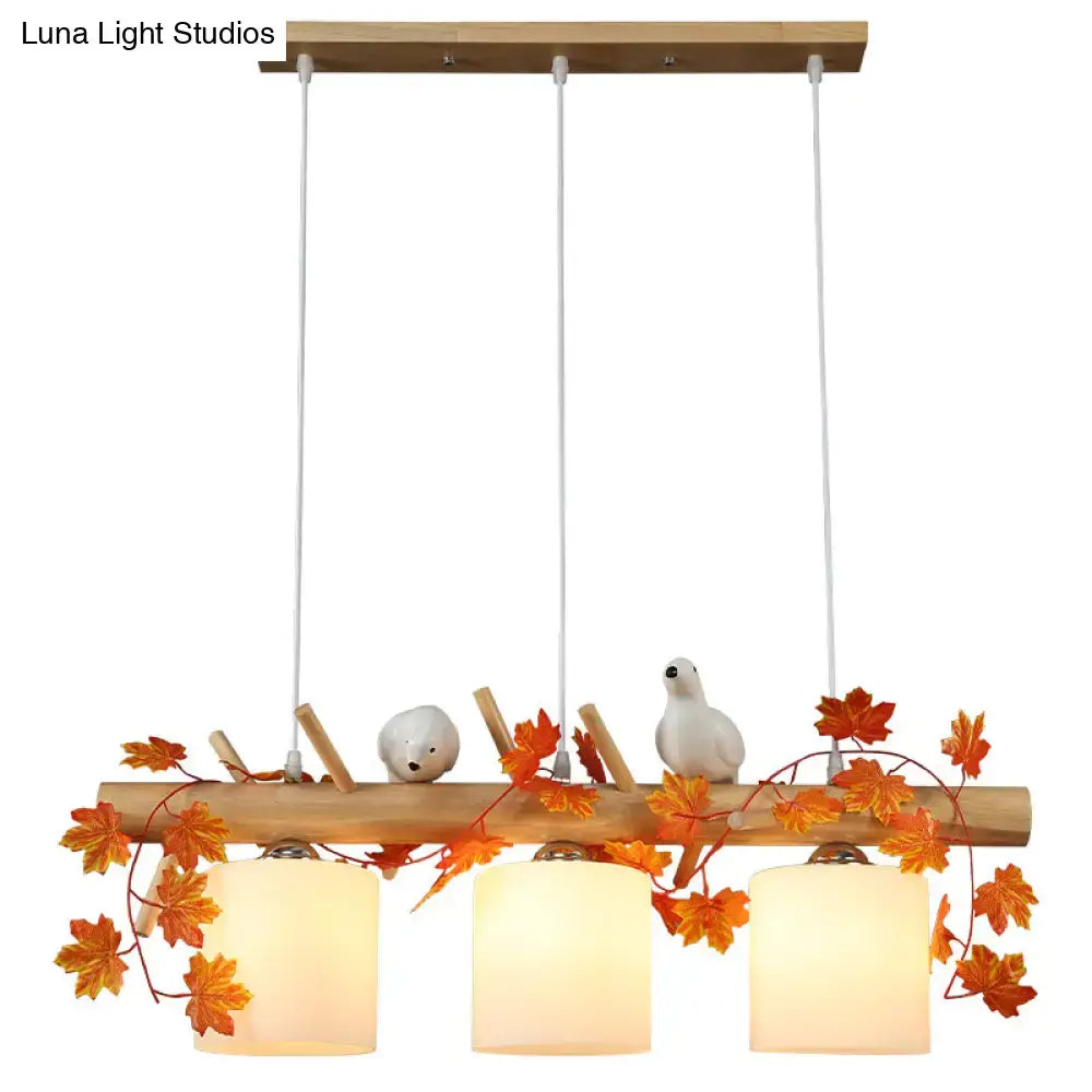 DecorBites™ modern wood linear island lighting with natural wood, warm glass shades, and orange maple leaf plant accents
