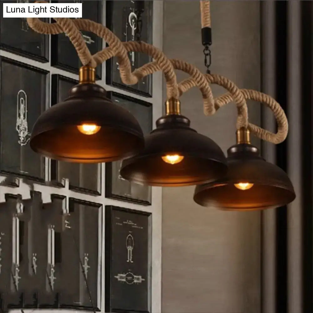 Rustic wooden beam three-light island pendant with dark matte metal shades brass accents and beige natural fiber rope suspension
