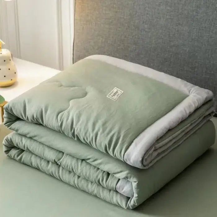 A soft sage green cooling cotton quilt with plush white lining and subtle stitching from decorbites cooling cotton collection