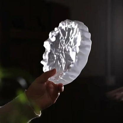 A translucent white crystal glass coaster with scalloped edges used as a minimalist jewelry display panel