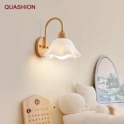 A minimalist scandinavian wall lamp with a white frosted glass shade, brass arm, and cream led wooden base
