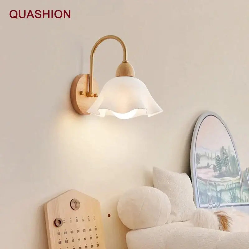 A minimalist scandinavian wall lamp with a white frosted glass shade, brass arm, and cream led wooden base