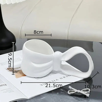 White ceramic bowknot ceramic coffee mug by decorbites shaped like a sculpted bow for kitchen tea use