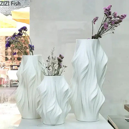 Sculpted white ceramic vase set by decorbites with flowing surfaces holding dried purple flowers for bedroom decor