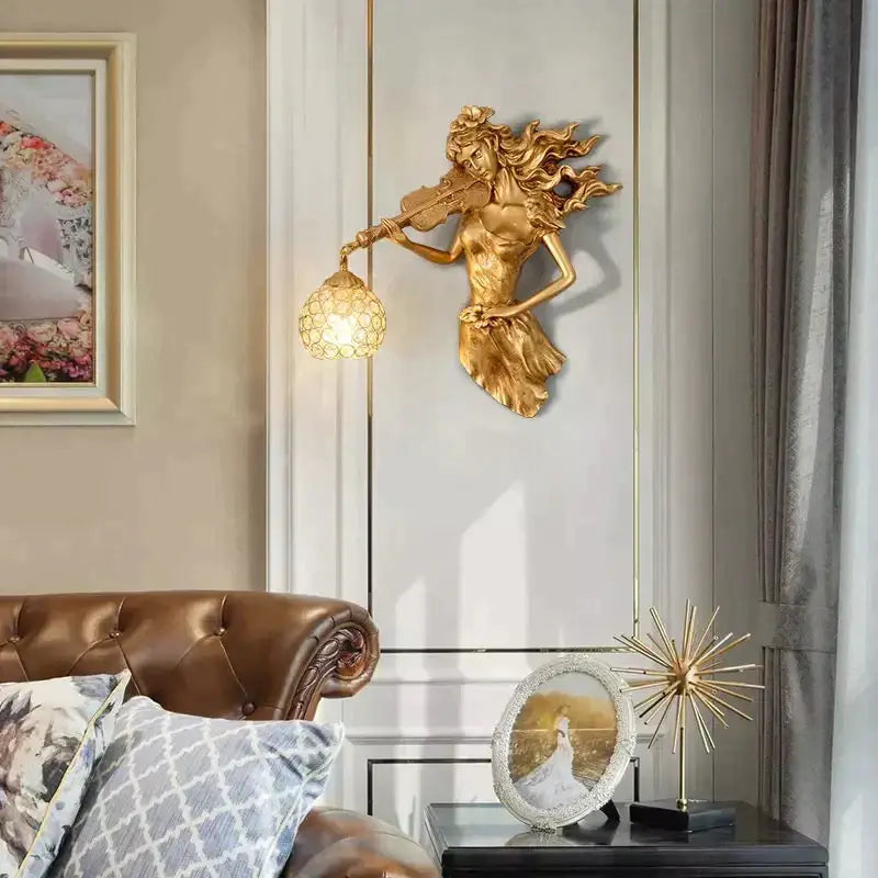 Gold wall lamp featuring a sculptural violinist figure with flowing hair and a crystal globe-shaped lampshade