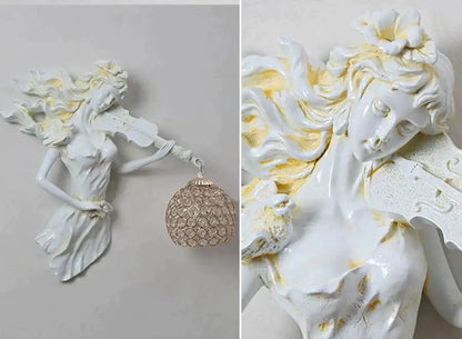 White ceramic wall lamp of a gold-accented violinist holding an ornate crystal pendant for living room sconce