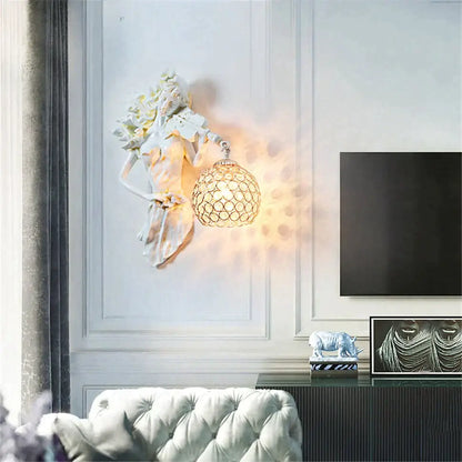 White sculpted wall lamp featuring a classical figure holding an ornate spherical crystal wall lampshade for living room