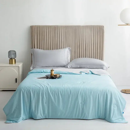 Light blue silky cooling queen quilt with subtle circular stitching for summer bedroom comfort