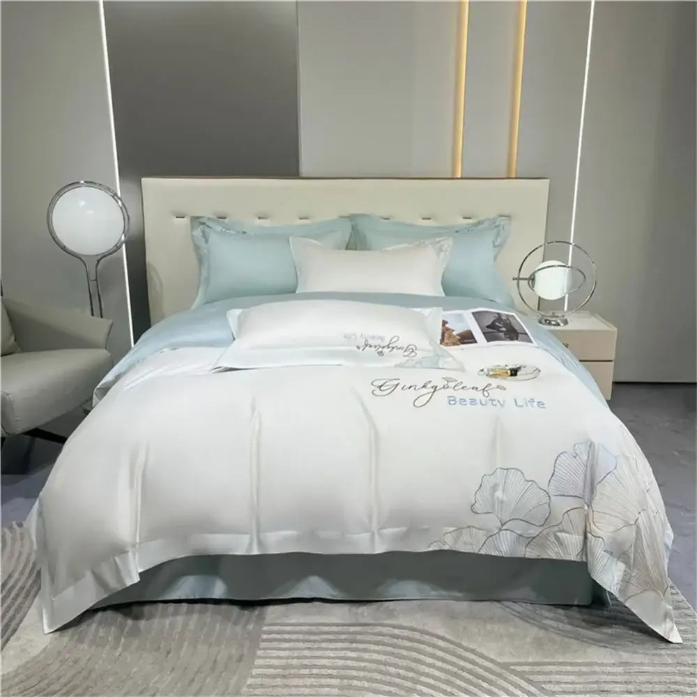 White satin duvet cover with silver embroidered ginkgo leaf and script paired with light blue pillows in 1200tc embroidery egyptian cotton bedding set