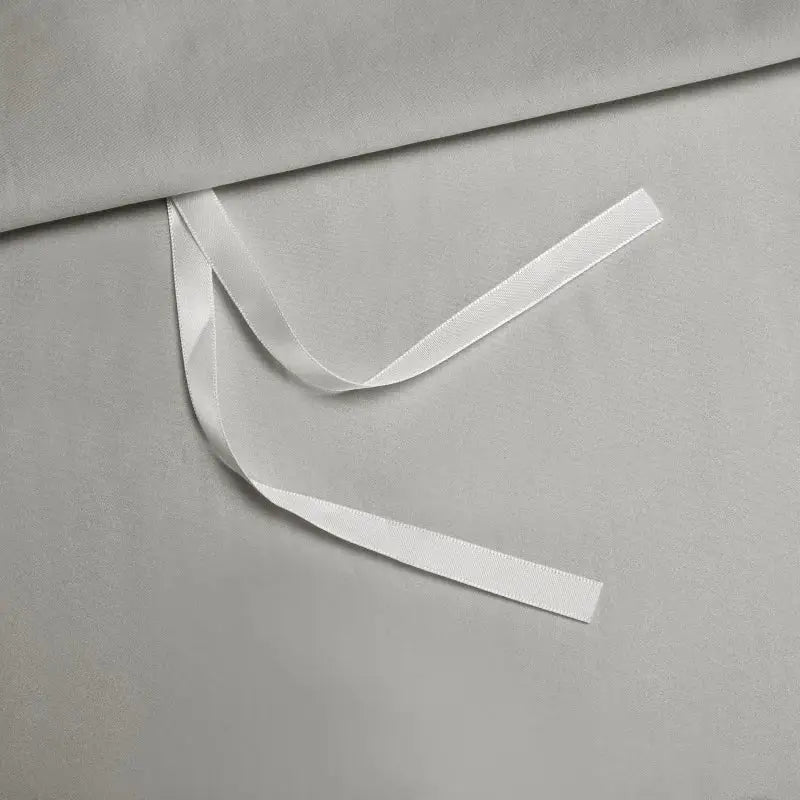 A smooth white satin ribbon on soft gray fabric showcasing the silver satin egyptian cotton bedding set decorbites 1000tc egyptian
