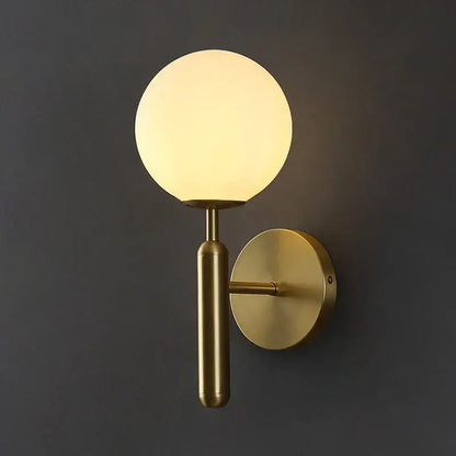 A sleek brass wall sconce lamp with a glowing spherical glass shade designed for corridor lighting
