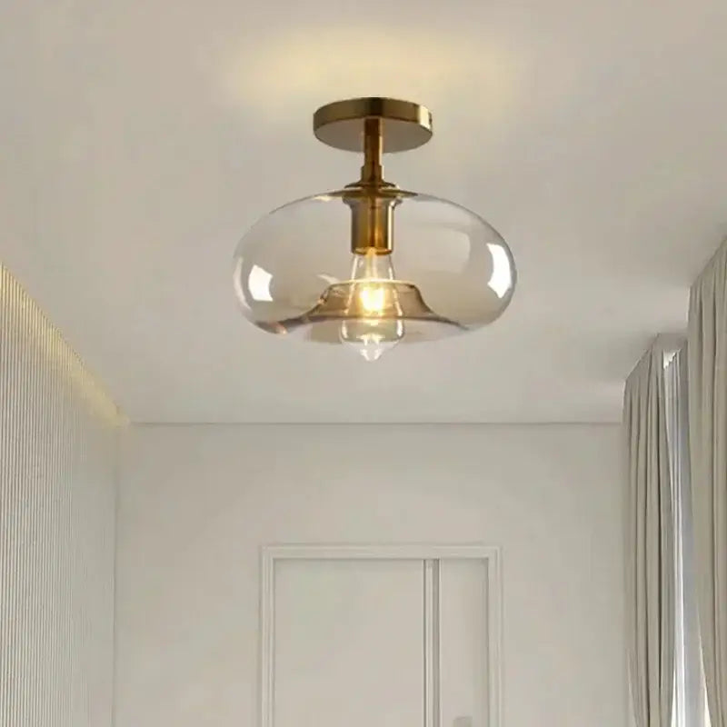 A modern brass-finished pendant light with a clear teardrop glass pendant ideal for dining room lighting