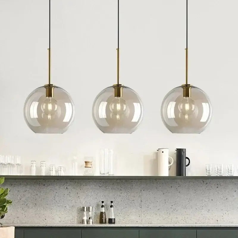 Three modern pendant lights with spherical smoked glass shades and brass-finished metal glass pendant for dining room