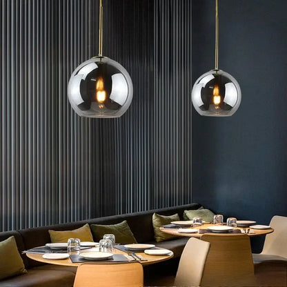 Two smoky gray glass pendant lights with gold-toned chains and iron finish serve as a stylish light source above dining area