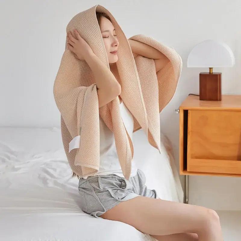 Soft beige decorbites cotton honeycomb towel blanket draped over a woman for living room couch use