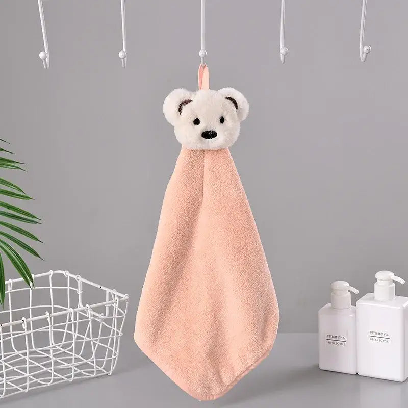 Soft peach-colored microfiber hand towel with decorbites cartoon bear design hanging from a pink loop for kitchen use