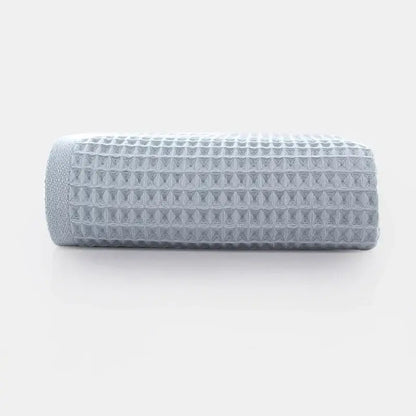 A neatly rolled soft gray cotton waffle towel with a textured grid pattern from the decorbites waffle towel bath set