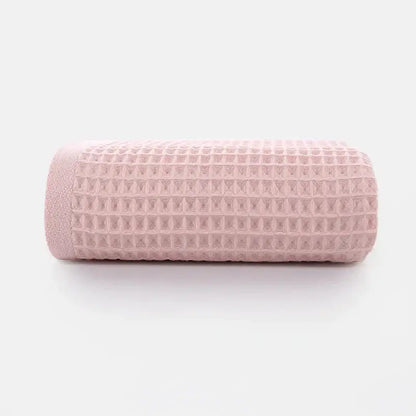 Soft gray blush blue cotton waffle towel bath set featuring a soft pink cotton waffle towel rolled to show texture