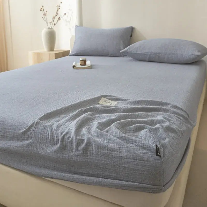 Soft light gray cotton fitted sheet with subtle wrinkles and a small label tag for bedroom decorbites cotton fitted use