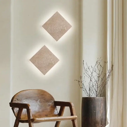 Two square beige yellow travertine led wall lamp sconces with textured surface and integrated backlighting for stairways