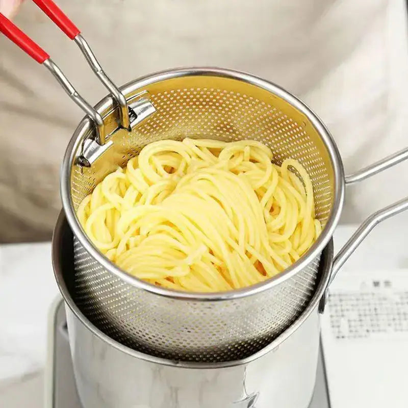 Stainless steel deep fryer pot with strainer and red-handled tongs lifting cooked yellow pasta by decorbites deep fryer