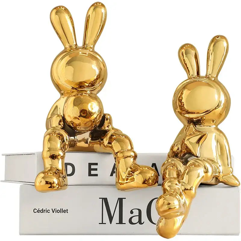 Two glossy gold ceramic rabbit sculpture set with rounded stylized features for living room decor