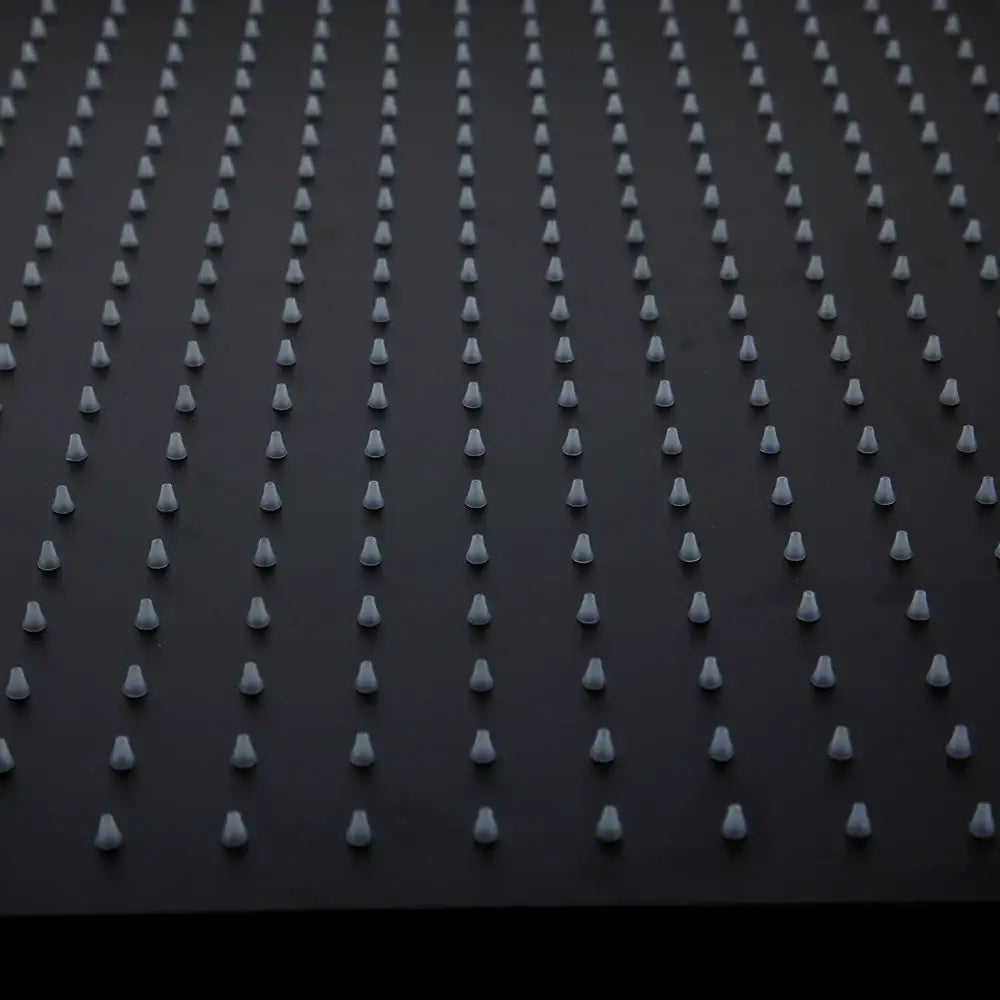 Rows of uniform white plastic spikes on the back side of a super slim matte black square rain shower head fixture