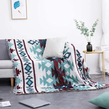 A teal sofa blanket with a dustproof butterfly carp pattern in teal maroon and white featuring fringed edges