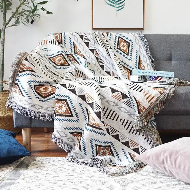 A cozy white sofa blanket with brown black and teal butterfly carp pattern and fringed edges for living room use