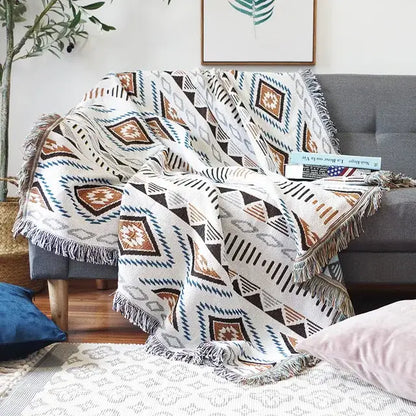 A cozy white sofa blanket with brown black and teal butterfly carp pattern and fringed edges for living room use