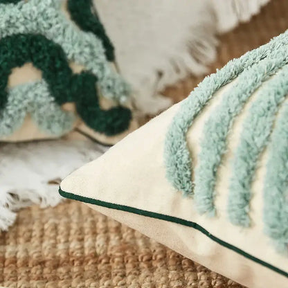 Cream-colored cushion case with light blue and dark green tufted leaf patterns and dark green stitched border decorbites geometric embroidery tassel