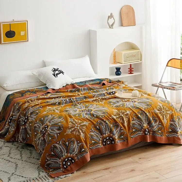 Warm mustard-yellow throw blanket with intricate floral paisley patterns made of soft geometric cotton gauze summer fabric