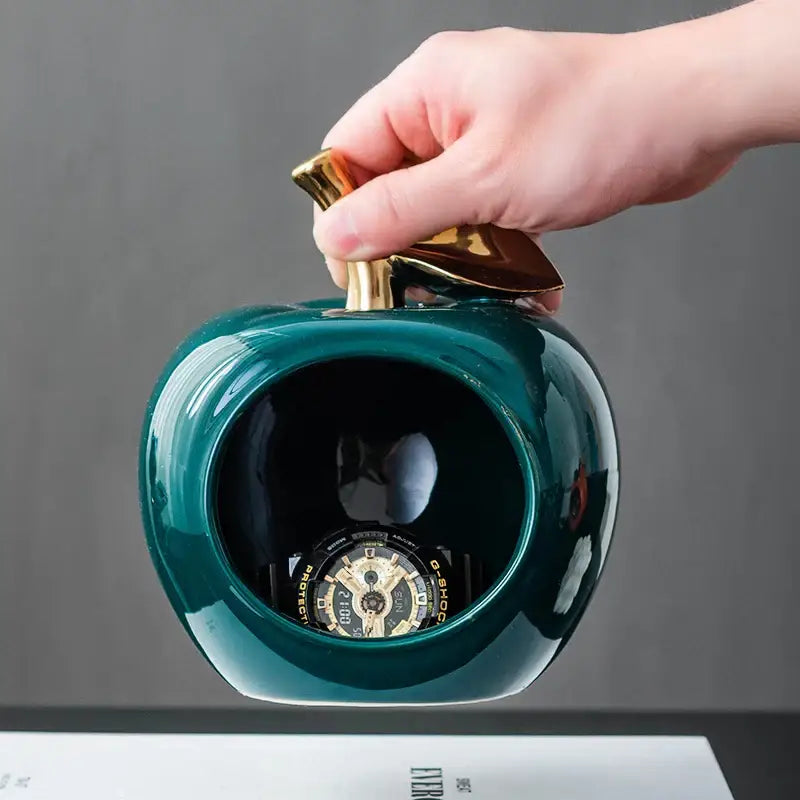 Teal ceramic apple storage box with gold toned leaf handle designed as a stylish living room storage box