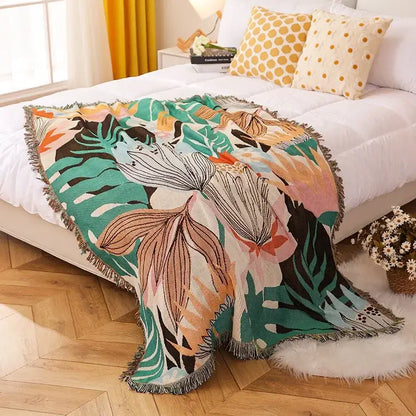 A vibrant tropical leaf-patterned decorbites knitted nordic outdoor sofa throw with fringe in bold greens and oranges