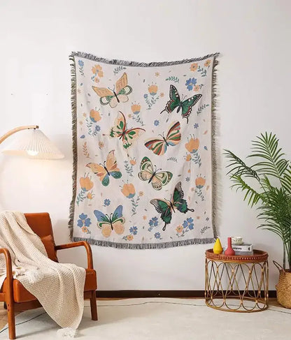 A cream woven decorbites knitted nordic outdoor sofa blanket with vibrant butterfly and floral patterns and fringed edges