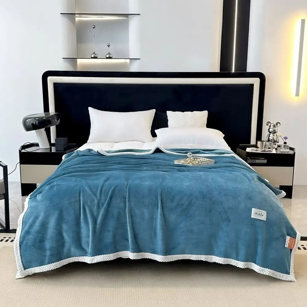 A cozy flannel nap blanket in teal with white scalloped edges and a soft velvety plush throw texture