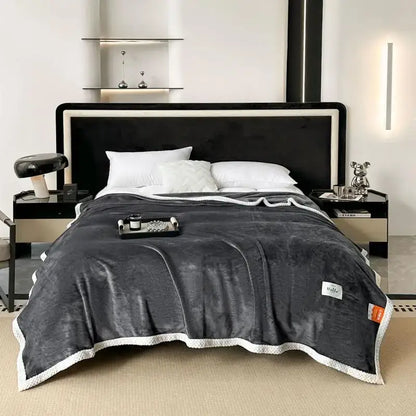 Dark gray plush throw blanket with white textured border and brand tag, a cozy flannel nap blanket for bedroom use