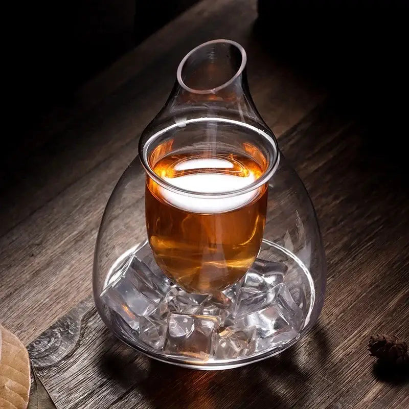 Teardrop glass wine pot with amber liquid on matching glass base surrounded by ice cubes for dining room and bar