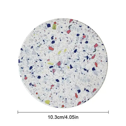 Circular decorbites diatomite coaster with white terrazzo finish featuring red blue green and gray mosaic fragments