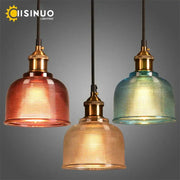 Three glass pendant lights with textured amber gold and teal shades and brass-finished fixtures for dining rooms