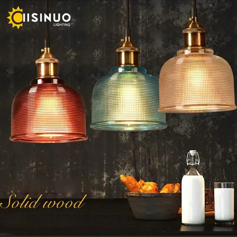 Three vintage-style glass pendant lights with textured red, teal, and amber shades and brass fixtures for dining room use
