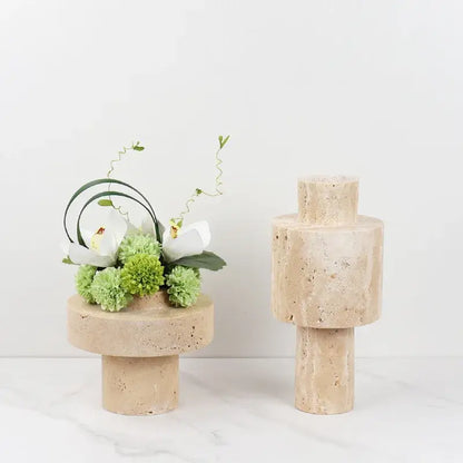 Beige travertine stone vase with textured tiered cylindrical design on a beige stone pedestal for dining room decorbites