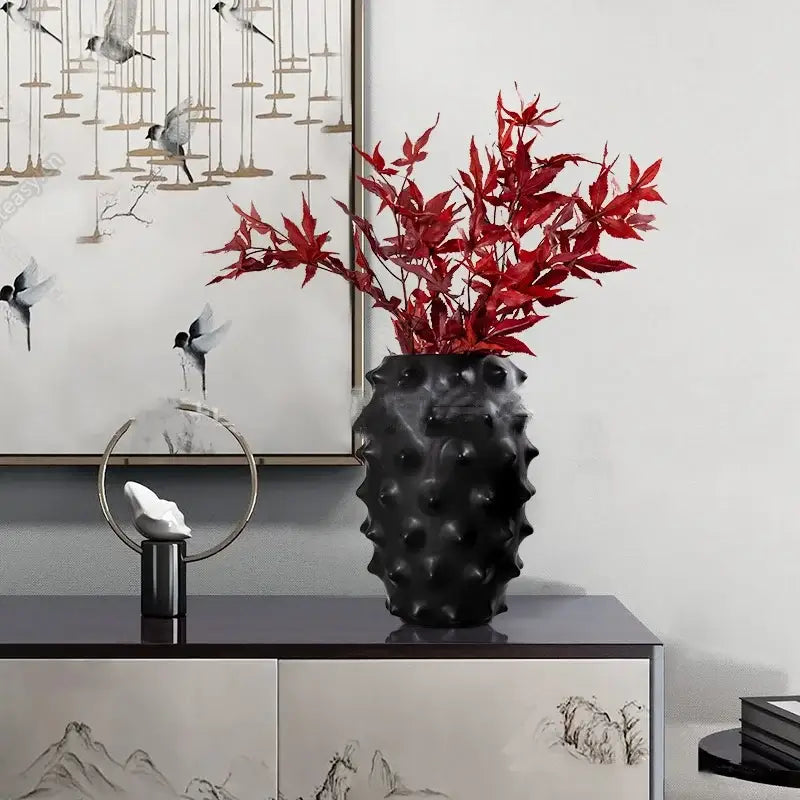 Textured black ceramic flower vase with spiky surface holding red artificial maple leaves for decorbites black ceramic decor