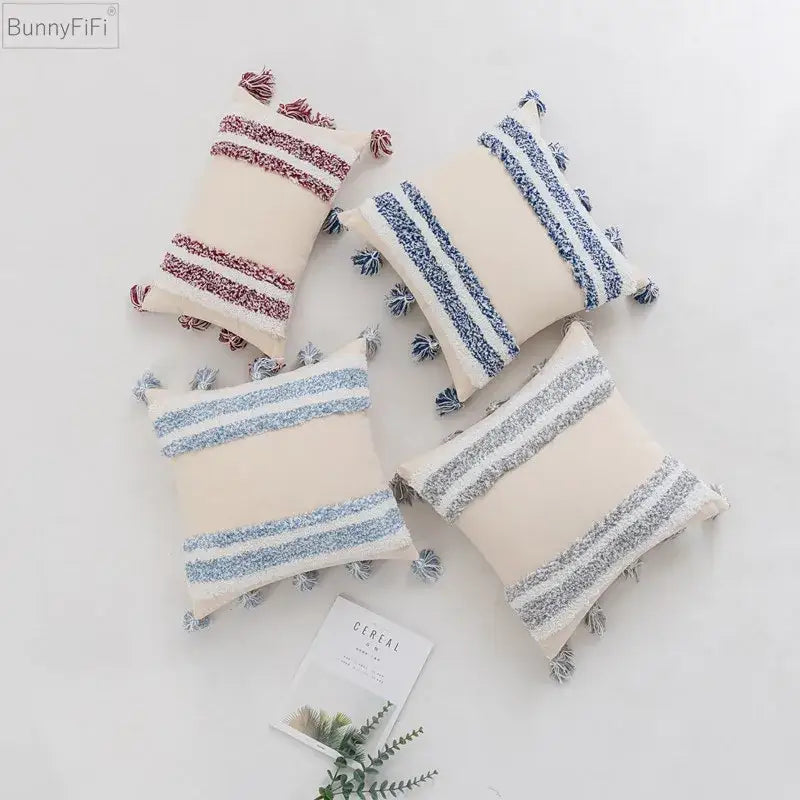 Cream-colored cushion cover with textured blue grey and dusty rose stripes and tassels for stylish home decor by decorbites