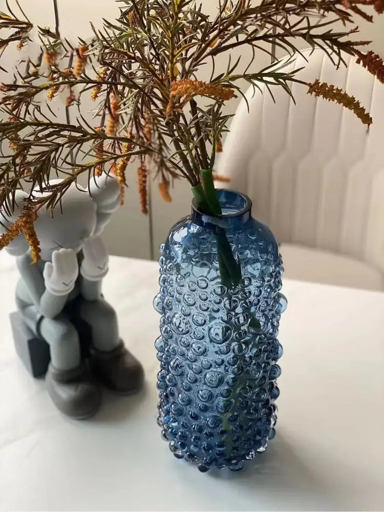 Textured blue glass flower vase with bubble-like surface holds dried greenery and orange-brown flowers for decorbites clear glass decor